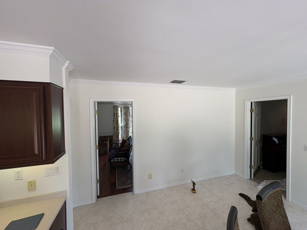 Kitchen feature wall after painting, with a smooth light finish and white crown molding