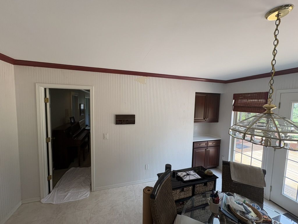Breakfast nook before painting, with striped walls and dark red crown molding