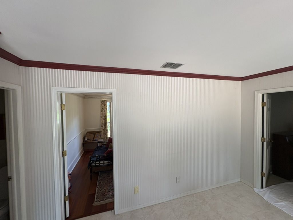 Kitchen feature wall before painting, with striped wall covering and dark red crown molding