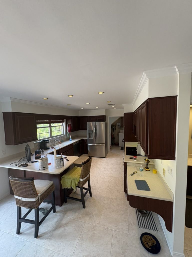 Kitchen after painting, with light walls and crisp white crown molding above dark wood cabinets
